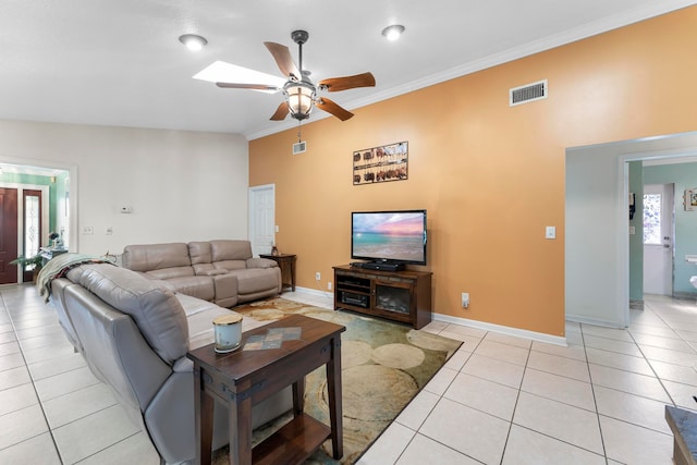 tiled living room featuring lofted ceiling with skylight, ceiling fan, and crown molding