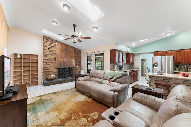 living room featuring ceiling fan, vaulted ceiling with skylight, and light tile patterned floors