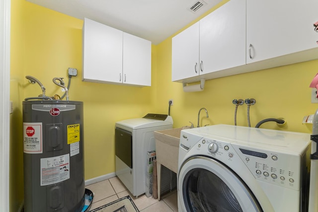 washroom with cabinets, light tile patterned flooring, washer and dryer, and water heater