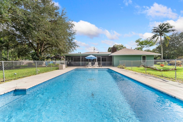 view of swimming pool featuring a yard and a sunroom