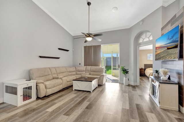 living room featuring crown molding, a towering ceiling, light hardwood / wood-style floors, and ceiling fan