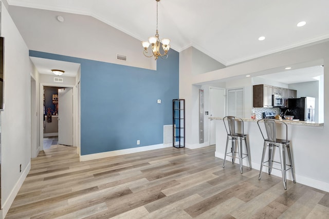 kitchen featuring kitchen peninsula, light hardwood / wood-style floors, ornamental molding, and appliances with stainless steel finishes