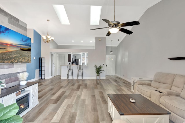 unfurnished living room with vaulted ceiling, crown molding, light hardwood / wood-style floors, and ceiling fan with notable chandelier