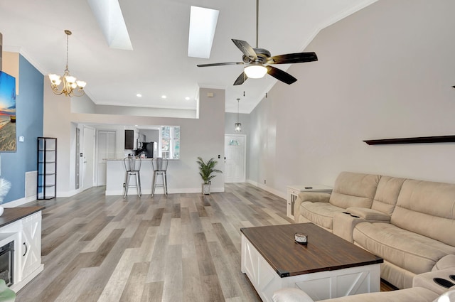 living room featuring a skylight, light hardwood / wood-style flooring, high vaulted ceiling, crown molding, and ceiling fan with notable chandelier