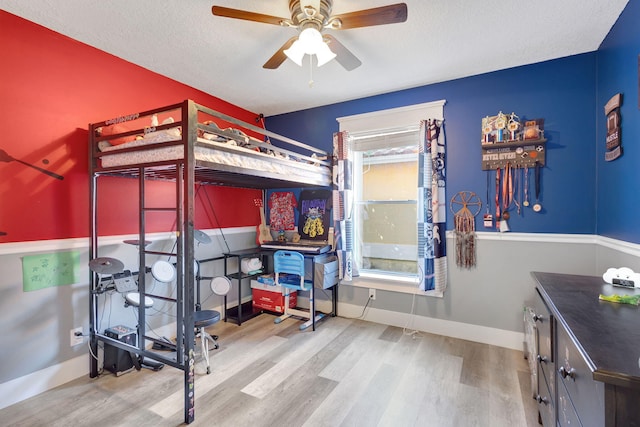 bedroom with hardwood / wood-style flooring, ceiling fan, and a textured ceiling