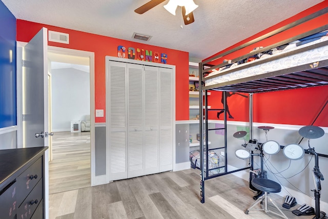 bedroom with hardwood / wood-style floors, ceiling fan, a textured ceiling, and a closet