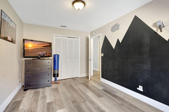 unfurnished bedroom featuring a textured ceiling, light hardwood / wood-style flooring, and a closet