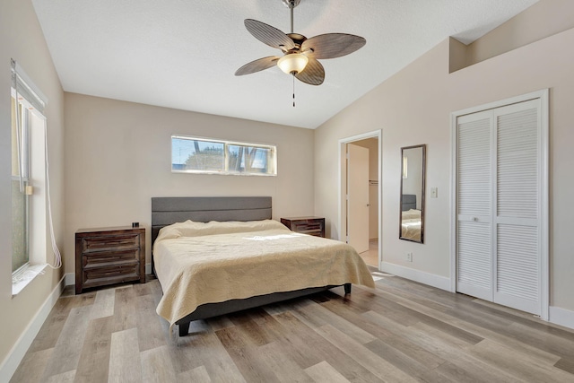 bedroom with ceiling fan, a closet, light hardwood / wood-style floors, and vaulted ceiling