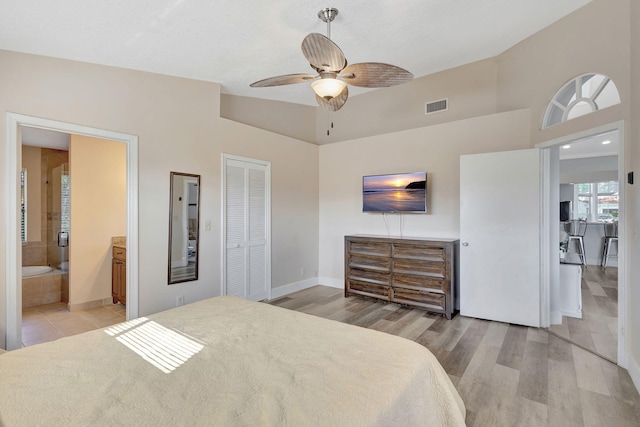 bedroom featuring a closet, connected bathroom, light hardwood / wood-style floors, and ceiling fan