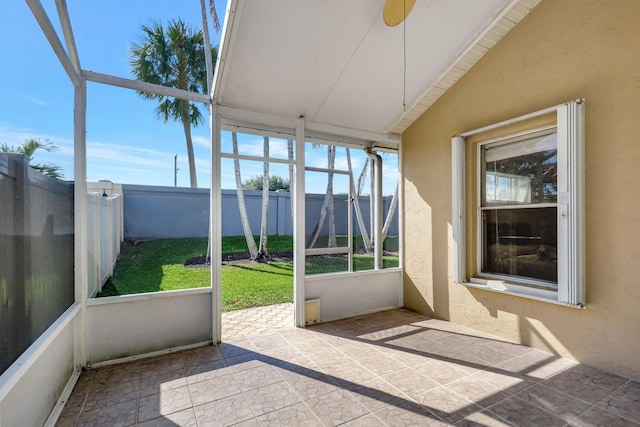 unfurnished sunroom featuring ceiling fan, a healthy amount of sunlight, and vaulted ceiling