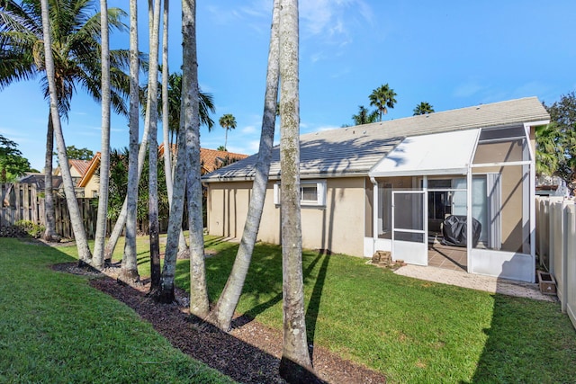 rear view of house featuring a yard and a sunroom