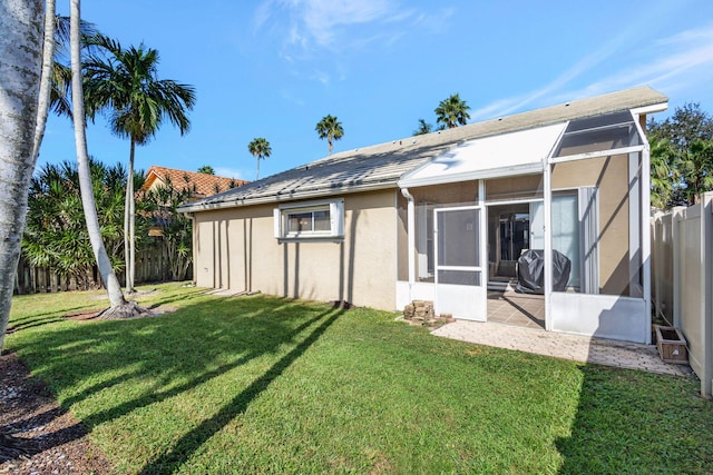 rear view of house with a sunroom and a yard