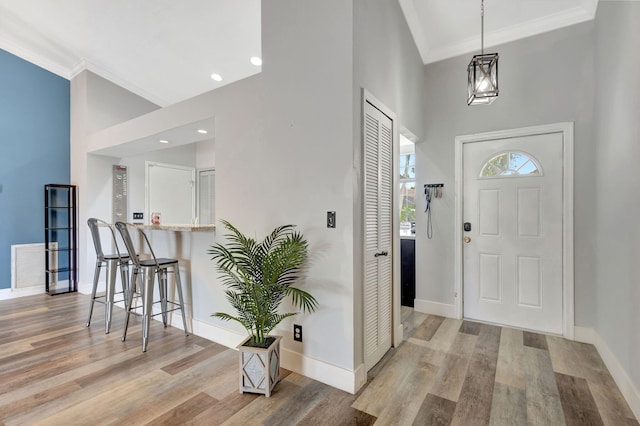 entrance foyer featuring a high ceiling, light hardwood / wood-style floors, and crown molding