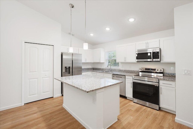 kitchen featuring stainless steel appliances, white cabinetry, hanging light fixtures, light hardwood / wood-style floors, and a center island