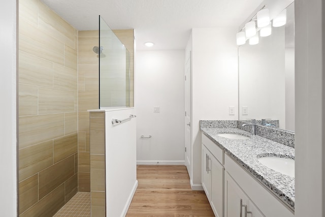 bathroom featuring tiled shower, vanity, and hardwood / wood-style flooring