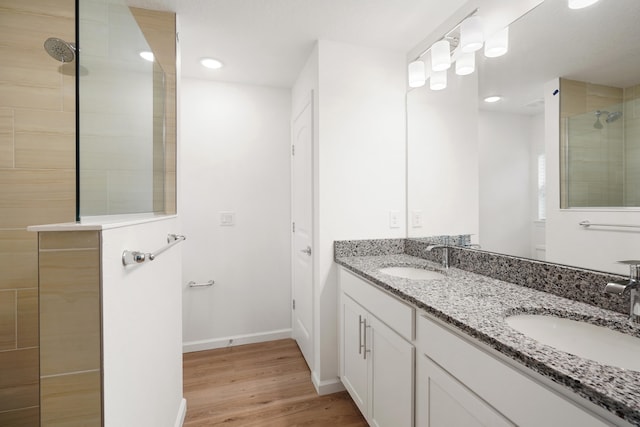 bathroom with hardwood / wood-style floors, vanity, and a tile shower