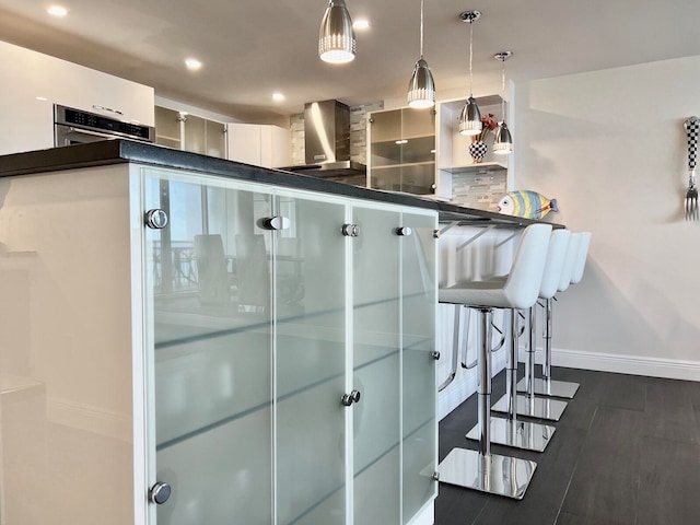 kitchen featuring white cabinets, dark wood-type flooring, oven, and decorative light fixtures