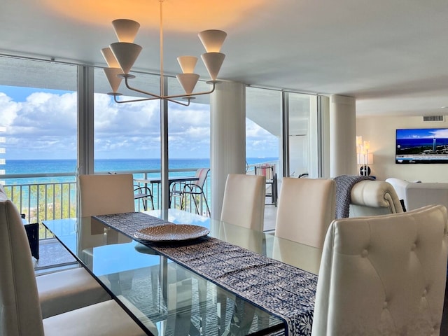 dining space with a water view, a wall of windows, and a notable chandelier