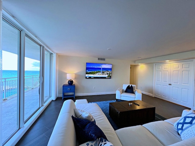 living room with dark hardwood / wood-style flooring and a water view