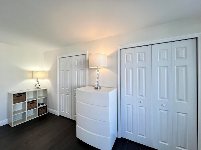 bedroom featuring dark hardwood / wood-style flooring and two closets