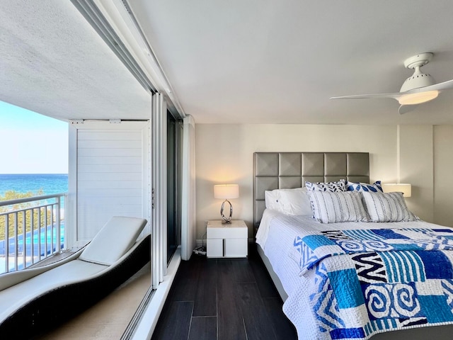 bedroom with ceiling fan, a water view, and dark hardwood / wood-style flooring