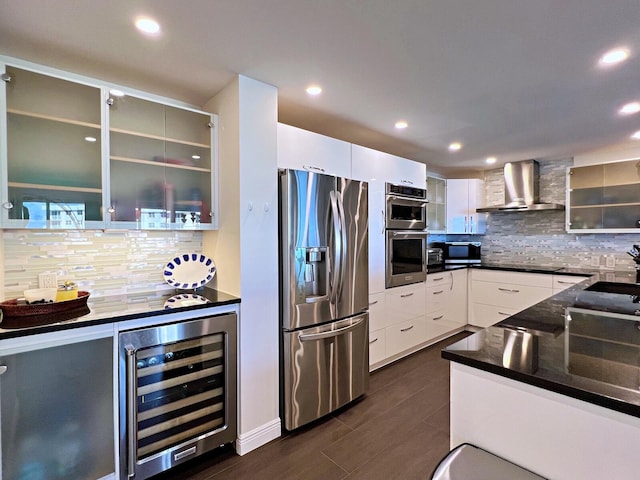 kitchen featuring stainless steel appliances, wine cooler, backsplash, white cabinets, and wall chimney exhaust hood