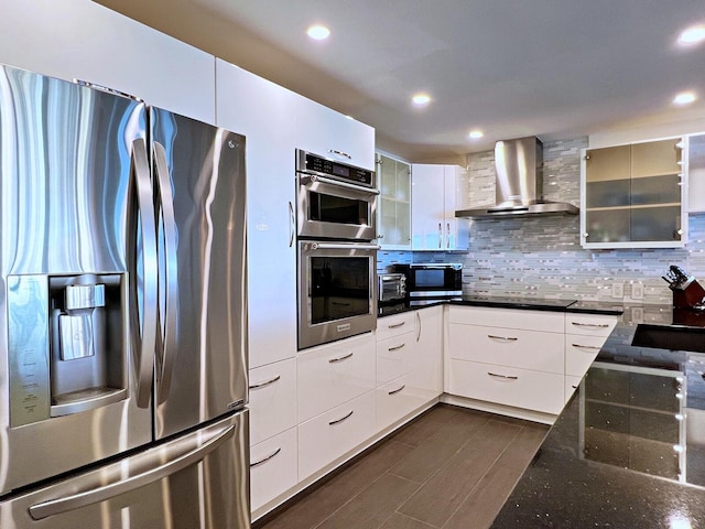 kitchen featuring stainless steel appliances, dark hardwood / wood-style flooring, decorative backsplash, white cabinets, and wall chimney exhaust hood