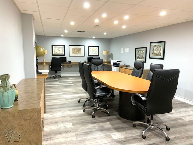 home office with light hardwood / wood-style floors and a drop ceiling