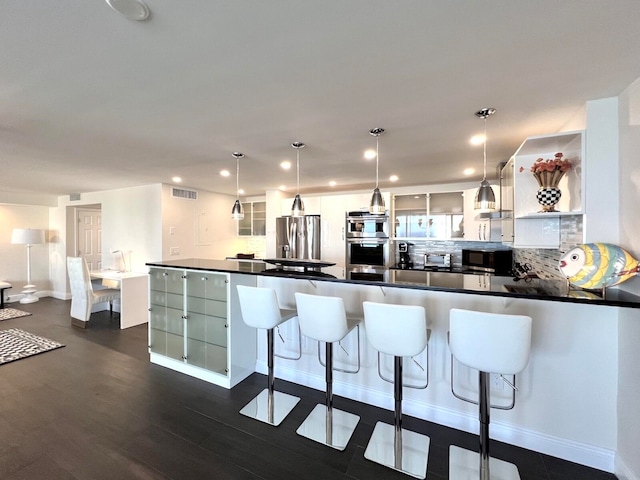 kitchen featuring stainless steel appliances, white cabinetry, tasteful backsplash, dark wood-type flooring, and pendant lighting