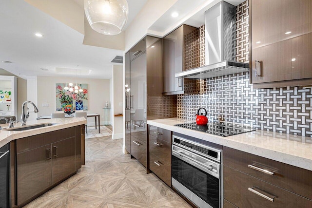 kitchen with black electric cooktop, stainless steel oven, pendant lighting, and wall chimney range hood