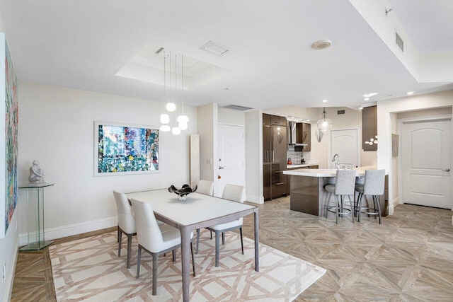 dining space with a raised ceiling and light parquet floors