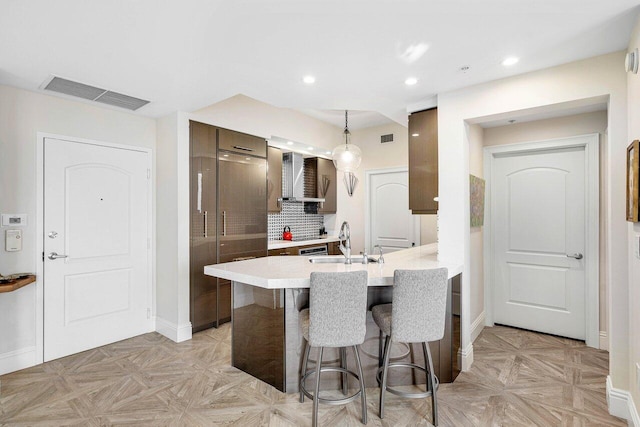 kitchen with sink, a kitchen breakfast bar, light parquet floors, decorative light fixtures, and decorative backsplash