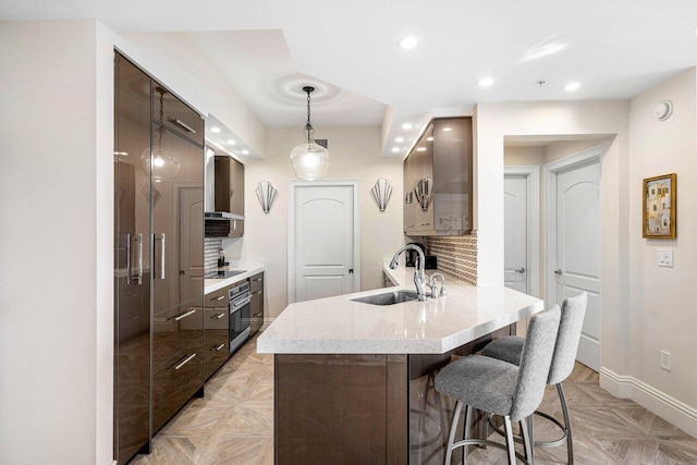 kitchen with black electric stovetop, sink, wall chimney exhaust hood, tasteful backsplash, and kitchen peninsula