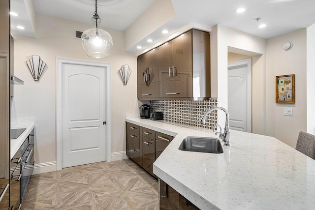 kitchen featuring sink, pendant lighting, decorative backsplash, black electric stovetop, and light parquet flooring