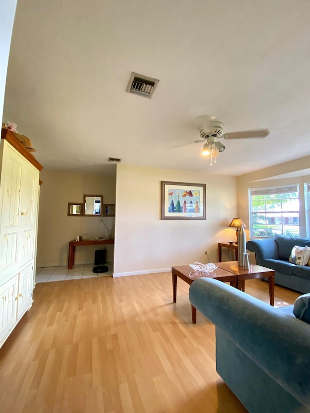 living room with light tile patterned flooring, ceiling fan, and wood walls