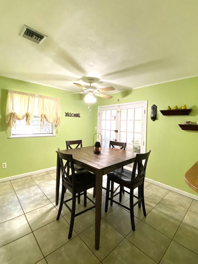 tiled dining room with ceiling fan and crown molding