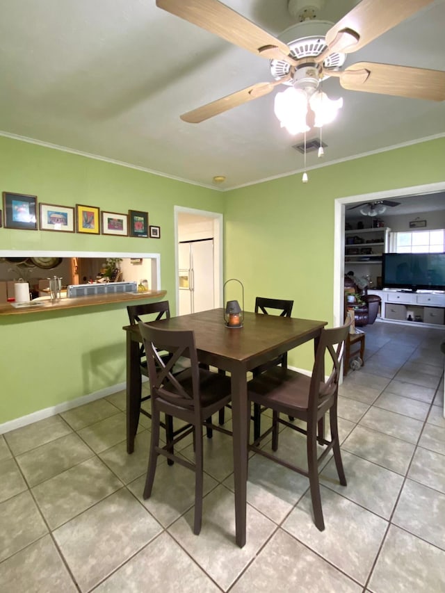 tiled dining space with ceiling fan, ornamental molding, and french doors