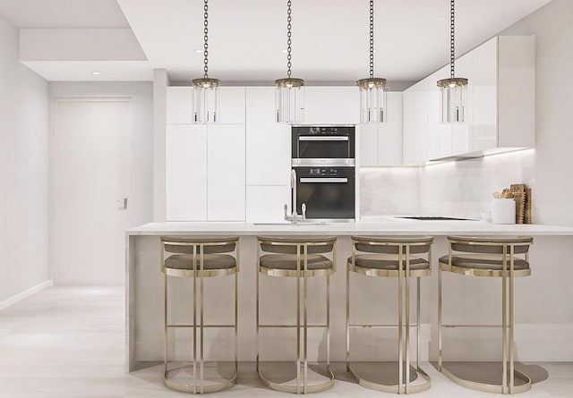 220 Lake Shore Dr Unit 1013, Lake Park, FL 33403 - kitchen featuring stainless steel double oven, decorative backsplash, a breakfast bar area, and white cabinetry