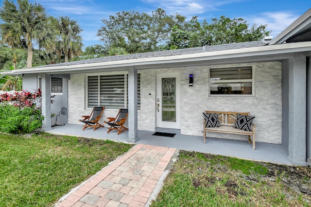 entrance to property featuring a porch and a lawn