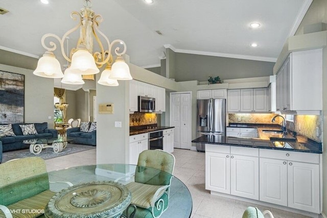 kitchen featuring dark countertops, stainless steel appliances, light tile patterned flooring, lofted ceiling, and a chandelier