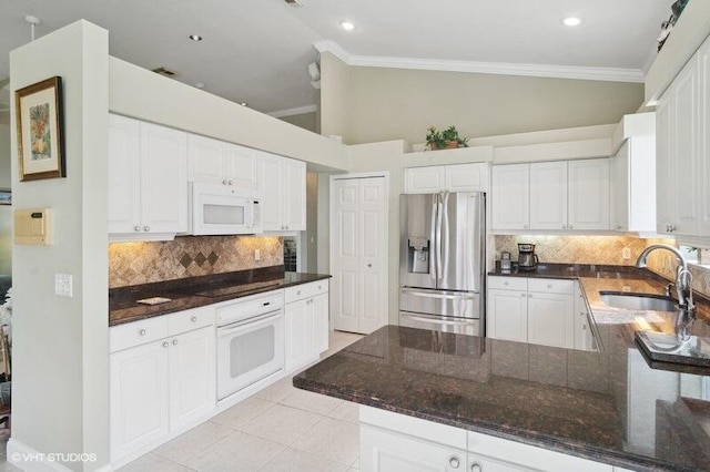 kitchen with sink, kitchen peninsula, white appliances, white cabinets, and vaulted ceiling