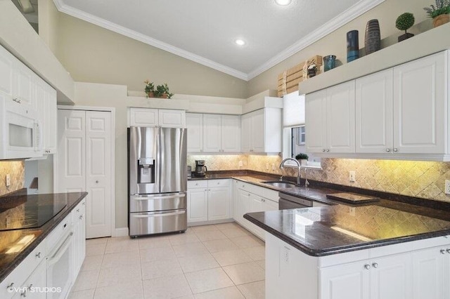 kitchen featuring stainless steel appliances, lofted ceiling, decorative backsplash, crown molding, and white cabinetry