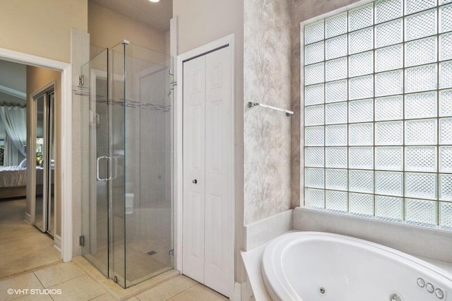 bathroom featuring tile patterned floors, a tub with jets, a shower stall, and a closet