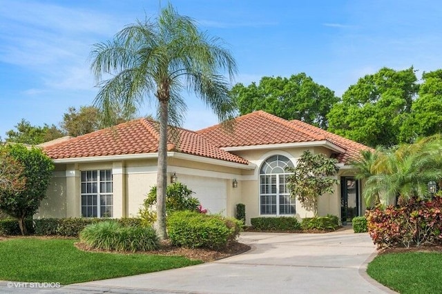 mediterranean / spanish-style home with a tile roof, an attached garage, driveway, and stucco siding