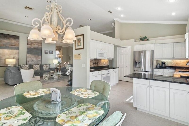 tiled dining area with sink, vaulted ceiling, a notable chandelier, and ornamental molding