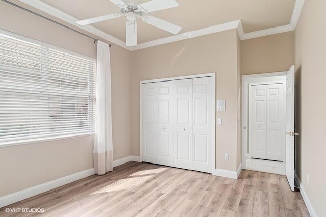 unfurnished bedroom with light wood-style flooring, ornamental molding, a ceiling fan, a closet, and baseboards