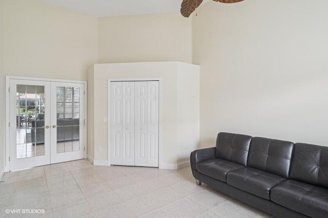 living room with light tile patterned floors, french doors, baseboards, and a towering ceiling