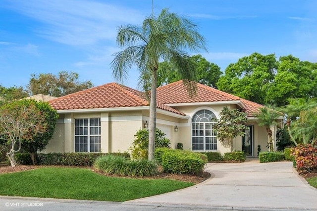 view of front of property featuring stucco siding, driveway, a tile roof, a front yard, and a garage