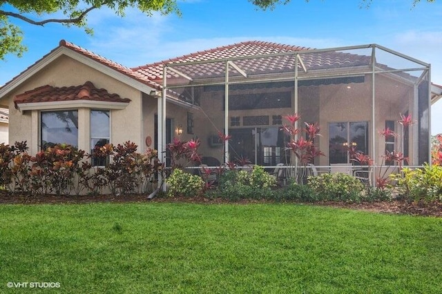 rear view of property featuring glass enclosure, a tiled roof, a yard, and stucco siding