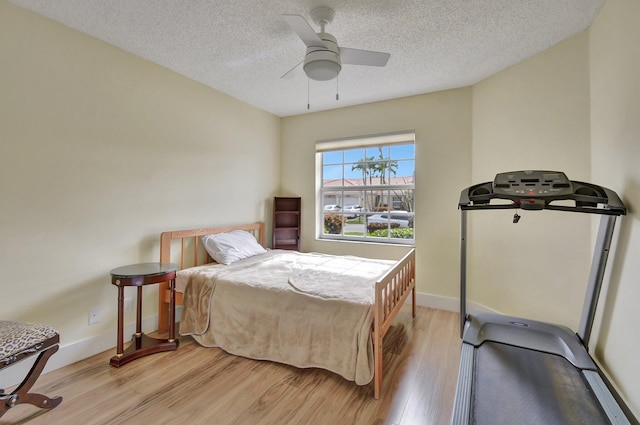 bedroom with ceiling fan, light hardwood / wood-style flooring, and a textured ceiling